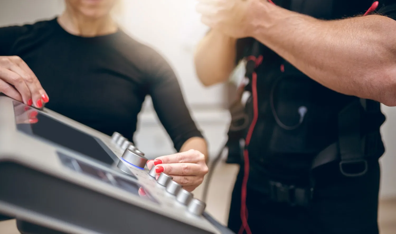 Trainerin stellt das EMS-Gerät für ein Training ein