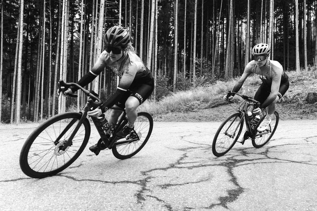 Zwei Radsportler in einer Kurve auf einer Waldstraße