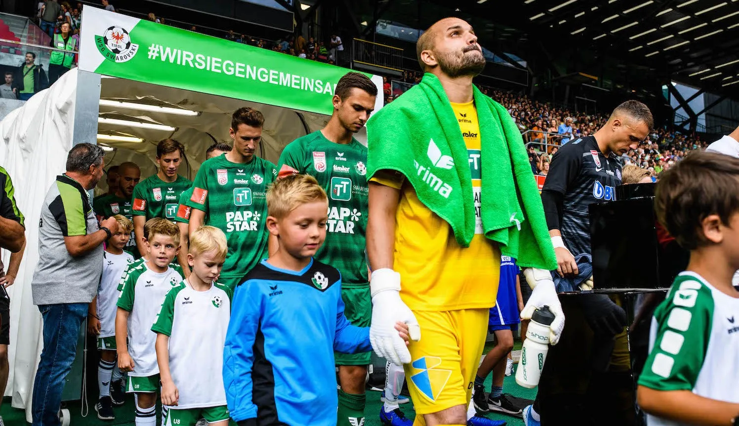 Spieler der WSG Tirol laufen mit Kindern ins Stadion ein